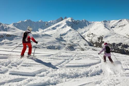 two people skiing down a snow covered mountain at Hotel l'Aigle in Valmeinier