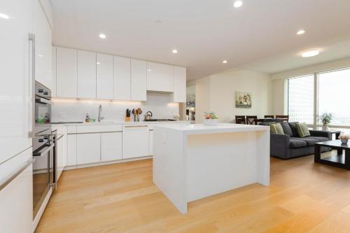 a kitchen with white cabinets and a living room at Cozy 3BR High Rise with Pool with great views in Los Angeles