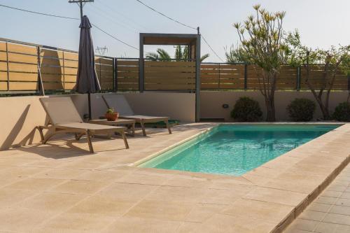 a swimming pool with an umbrella and a chair and a table and an umbrella at Villa Merlin in Galatás