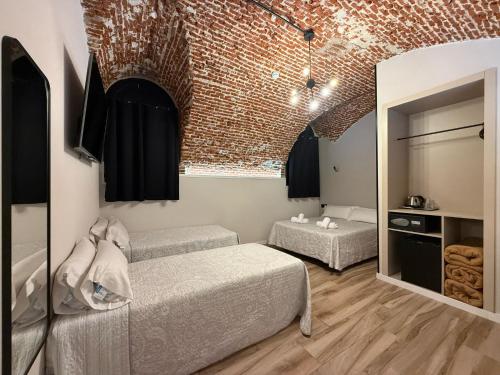 a bedroom with two beds and a brick wall at CC Opera Suites in Madrid