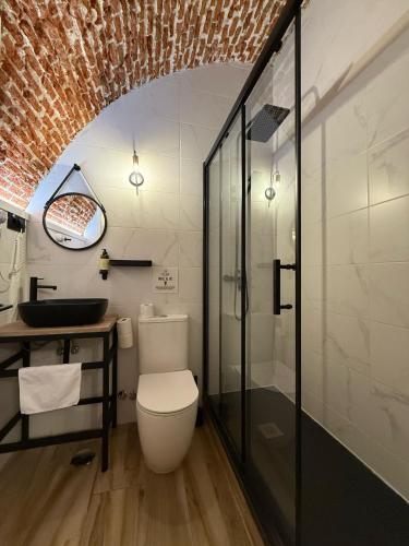 a bathroom with a toilet and a glass shower at CC Opera Suites in Madrid