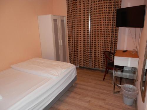 a bedroom with a bed and a desk and a television at Relax Hotel-Ludwigshafen in Ludwigshafen am Rhein