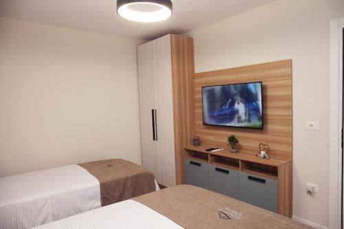a bedroom with two beds and a tv on the wall at Dream House Enia 4 in Shkodër