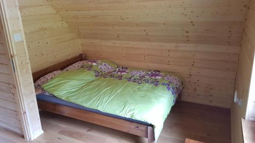 a bed in a room with a wooden wall at Domek u Pusi in Solina