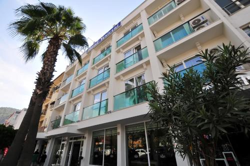 a building with a palm tree in front of it at Yeniceri City Hotel in Fethiye