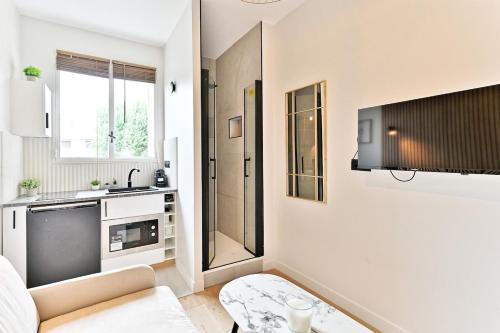 Il comprend un salon blanc avec un canapé et une cuisine. dans l'établissement Petit studio charmant près de Paris - III, à Neuilly-sur-Seine