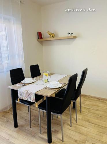 a dining room table with black chairs and a white table and chairsktop at Apartmány Komenského Velké Losiny in Velké Losiny
