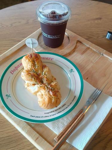 a plate with a pastry and a cup of coffee at Junior Family Room by 233Poshtel in Lampang