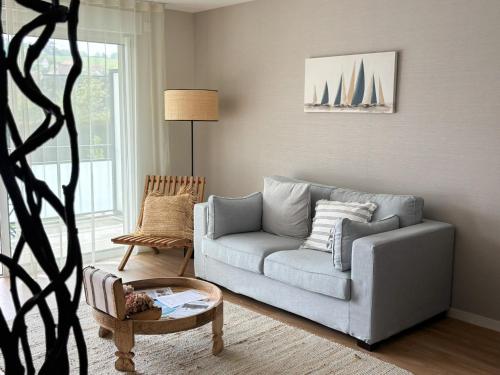 a living room with a gray couch and a table at Les Boréales - Appart'hotel & Restaurant in Villers-sur-Mer