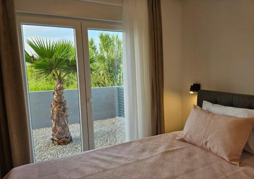 a bedroom with a bed and a window with a palm tree at Vila OASIS - Zadar, Vrsi in Vrsi