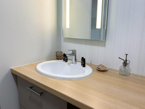 a bathroom with a white sink and a mirror at Les Boréales - Appart'hotel & Restaurant in Villers-sur-Mer