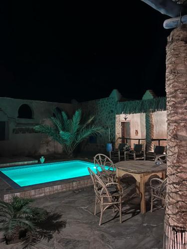 a table and chairs next to a pool at night at kasbah luna del sur in Erfoud