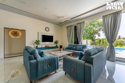 a living room with two blue couches and a tv at StayVista at Sky Hills with BBQ, Pool in Chinchavli