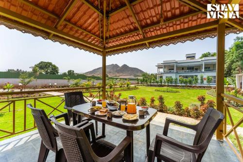 a table and chairs on a patio with a view at StayVista at Sky Hills with BBQ, Pool in Chinchavli