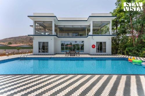 a house with a swimming pool in front of a house at StayVista at Sky Hills with BBQ, Pool in Chinchavli