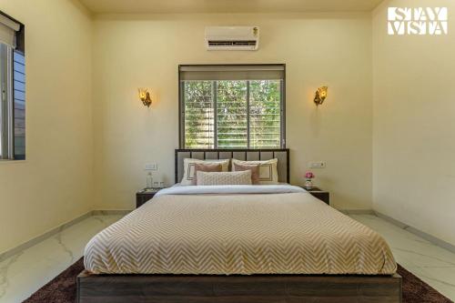 a bedroom with a large bed and a window at StayVista at Sky Hills with BBQ, Pool in Chinchavli
