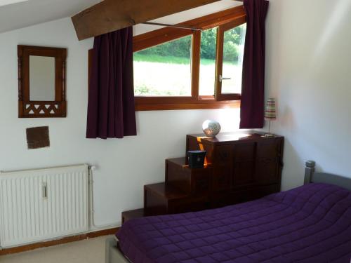 ein Schlafzimmer mit einem lila Bett und einem Fenster in der Unterkunft Le Nid du Lac, appartement en duplex au bord du lac d'Annecy, résidence avec plage privée in Doussard