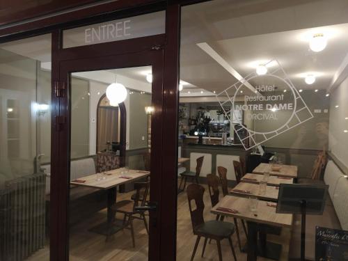 a restaurant with wooden tables and chairs in a room at Hôtel restaurant Notre Dame in Orcival
