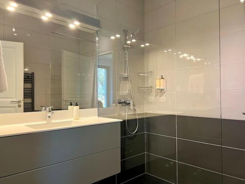 une salle de bain avec une douche, un lavabo et un miroir dans l'établissement Villa Greensome sur le Golf de Saint-Émilion, à Gardegan-et-Tourtirac