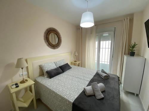 ein Schlafzimmer mit einem Bett und einem Spiegel an der Wand in der Unterkunft Casa Lotte, centro histórico,AC, garaje, wifi in Sanlúcar de Barrameda