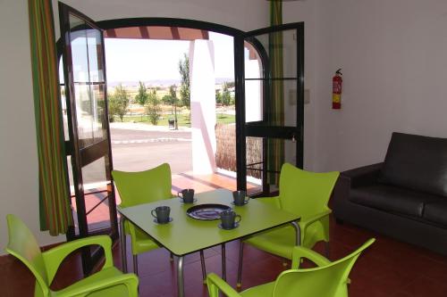 a living room with a table and green chairs at Camping la Sierrecilla in Humilladero