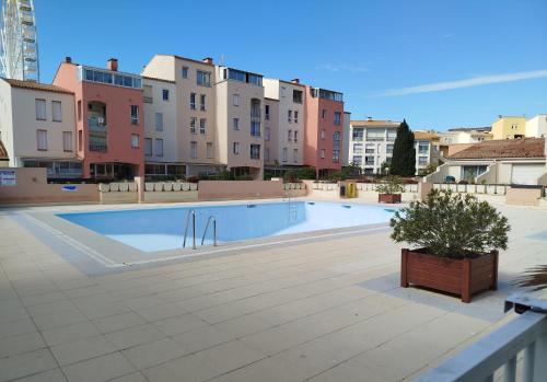 une grande piscine avec des bâtiments en arrière-plan dans l'établissement Cosy et Mer - Piscine partagée, au Cap d'Agde