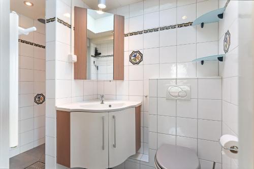 a bathroom with a sink and a toilet and a mirror at Linde 5 - Klepperstee Ouddorp met jacuzzi - NOT FOR COMPANIES in Ouddorp