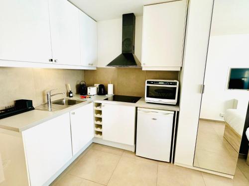 une cuisine avec des armoires blanches et un micro-ondes dans l'établissement Modern studio near the CROISETTE, à Cannes