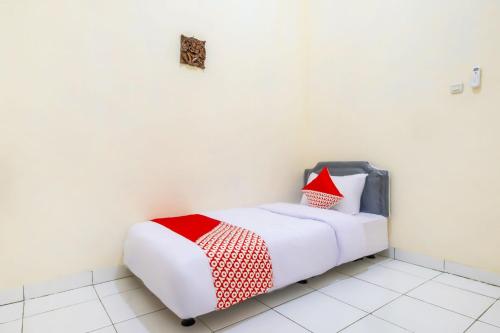a white bed with red and white pillows in a room at Hotel O Syariah Tasikmalaya Near Universitas Siliwangi Formerly Siliwangi Guest House in Tasikmalaya