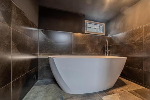 y baño con bañera y azulejos marrones. en Palima28, en Sankt Johann in Tirol