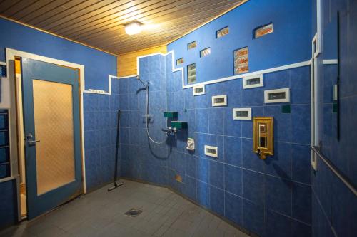 a bathroom with a shower and a blue wall at Vanhaselkä Cottage in Saariselka