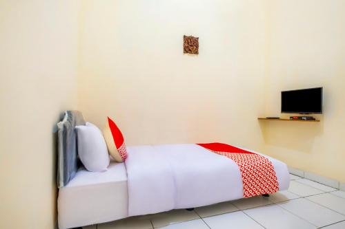 a bedroom with a white bed with red and white pillows at Hotel O Syariah Tasikmalaya Near Universitas Siliwangi Formerly Siliwangi Guest House in Tasikmalaya