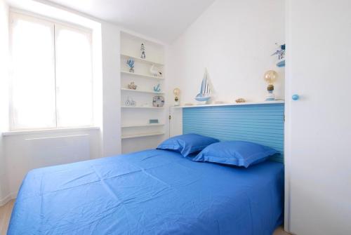 - un lit bleu avec des oreillers bleus dans une chambre dans l'établissement 130 Les gouverneurs 19, à Saint-Martin-de-Ré