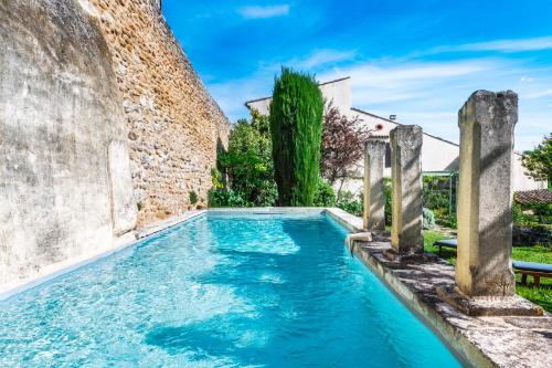 - une piscine en face d'un mur en pierre dans l'établissement Le Jardin suspendu, à Grignan