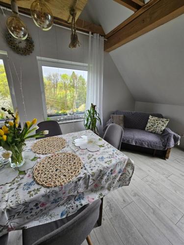 a dining room with a table and a couch at Porębana Osada in Długopole-Zdrój