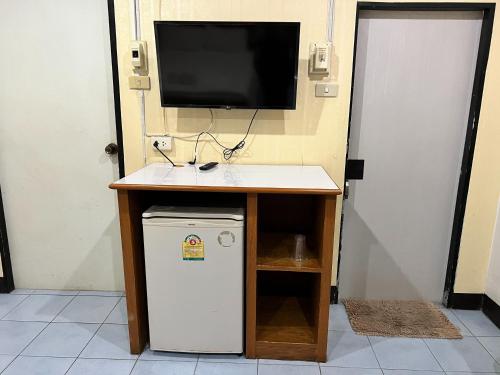 a tv sitting on top of a desk with a small refrigerator at Jamjuree Place in Ban Si Than