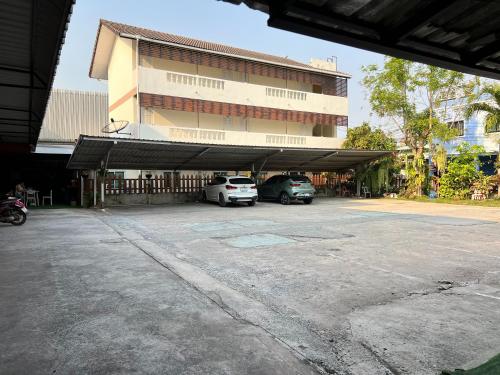 a building with two cars parked in a parking lot at Jamjuree Place in Ban Si Than
