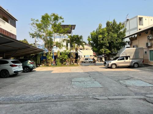 a parking lot with cars parked in front of buildings at Jamjuree Place in Ban Si Than