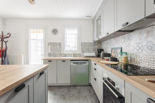 La cuisine est équipée de placards blancs et d'un lave-vaisselle vert. dans l'établissement Charmante maison pres plage et port, à Saint-Trojan-les-Bains