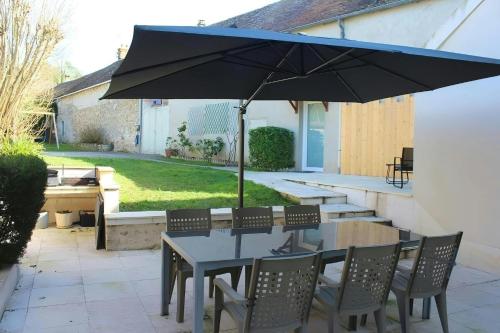 une table et des chaises avec un parasol sur une terrasse dans l'établissement Maison Familiale - Proche Fontainebleau Paris, à Champagne-sur-Seine