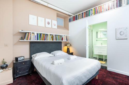 - une chambre avec un grand lit blanc et des étagères dans l'établissement GuestReady - Artist Loft with a Vertical Garden, à Paris