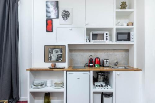 une cuisine avec des placards blancs et un comptoir dans l'établissement GuestReady - Artist Loft with a Vertical Garden, à Paris