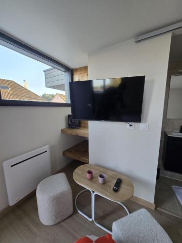 un salon avec une télévision et deux chaises et une table dans l'établissement Chambre Cosy Indépendante aux pieds des dunes, à Merlimont