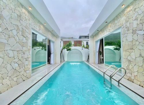 una piscina cubierta con agua azul y ventanas grandes en Villa Đà nẵng Lavender Luxury, en Da Nang