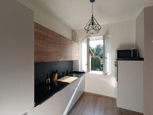 a kitchen with white cabinets and a black counter top at Casa Bianca, Vista unica sul lago di Como in Dervio