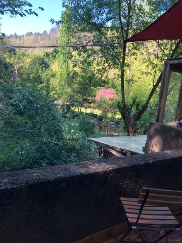 a picnic table and a chair next to a forest at Le Jardin in Rennes-les-Bains