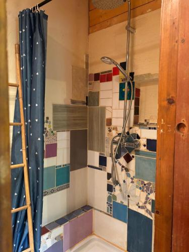 La salle de bains est pourvue d'une douche et d'un mur en carrelage. dans l'établissement Le Jardin, à Rennes-les-Bains