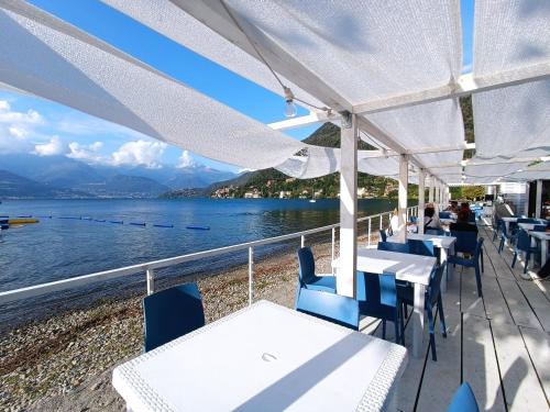 a restaurant with tables and chairs and a view of the water at Casa Bianca, Vista unica sul lago di Como in Dervio