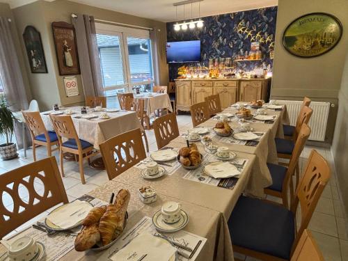 une salle à manger avec des tables et des chaises avec de la nourriture dans l'établissement Contact hôtel - Motel Les Bleuets & SPA, à Honfleur