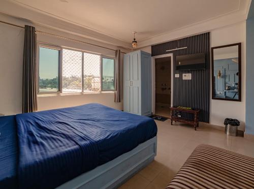 a bedroom with a blue bed and a mirror at The Bunkk Inn Hotel & Restaurant - Mussoorie International in Mussoorie